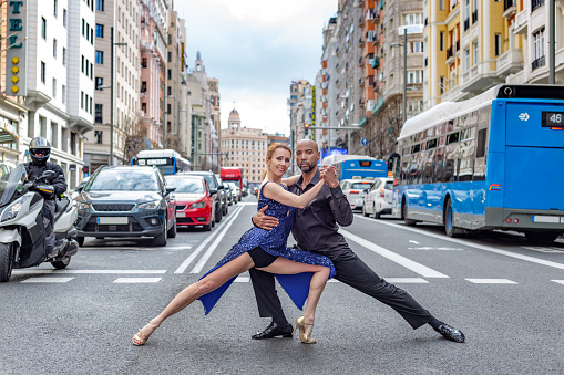 Madrid, Spain. March 9 2022. Multiracial dance couple poses looking at camera in pedestrian crossing of Madrid\