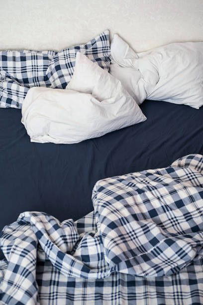 istock Rumpled bedding after sleep. Pillows, sheets and blanket, close up. 1388126904
