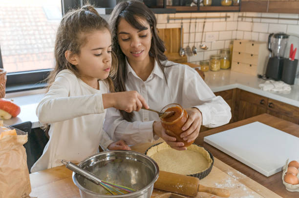 istock Mother and little daughter baking together in a home kitchen making a pie 1388129285