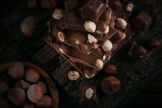 istock Pile of hazelnut milk chocolate and nuts on dark background 1388129299