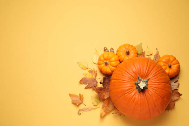 istock Flat lay composition with different ripe pumpkins and autumn leaves on yellow background. Space for text 1388135361