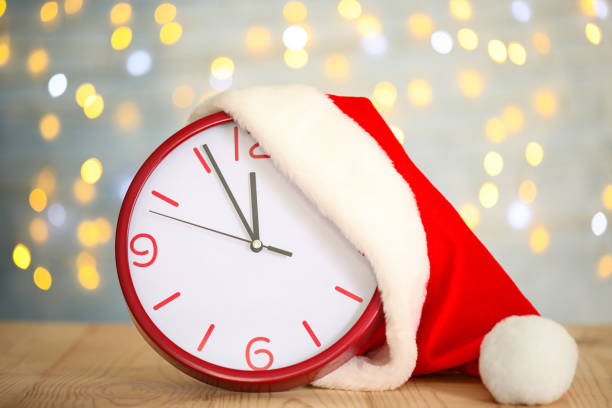 istock Clock with Santa hat showing five minutes until midnight on blurred background. New Year countdown 1388135395