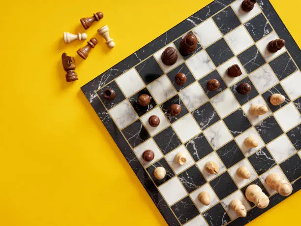 Photo of Top view of chessboard with chess pieces on yellow background