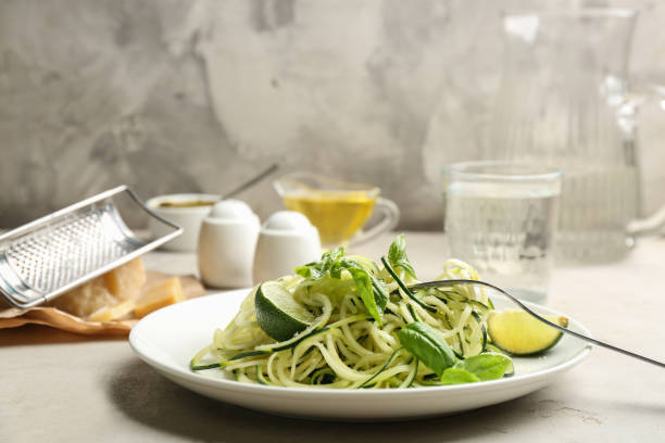 istock Delicious zucchini pasta with lime, grated cheese and basil on light table 1388137907