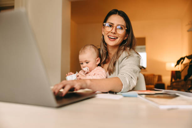 istock Happy single mom typing on a laptop in her home office 1388138039