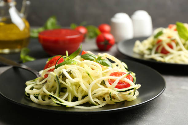 istock Delicious zucchini pasta with cherry tomatoes and basil on light grey table, closeup 1388138671