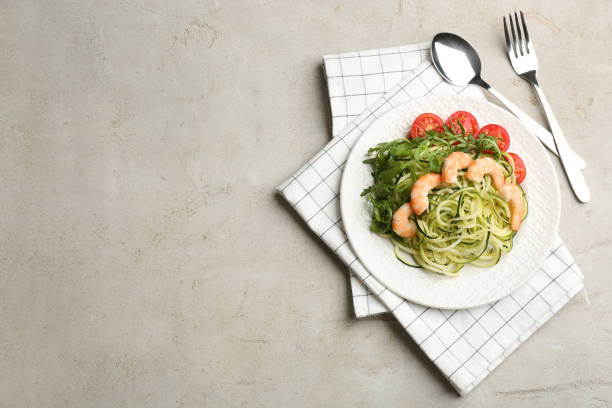 istock Delicious zucchini pasta with shrimps, cherry tomatoes and arugula served on light table, flat lay. Space for text 1388139246