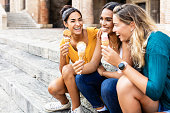 istock Happy multiracial women eating ice cream outdoors while sitting at the stairs 1388139309