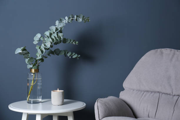istock Beautiful eucalyptus branches and burning candle on white table near blue wall. Interior element 1388140072