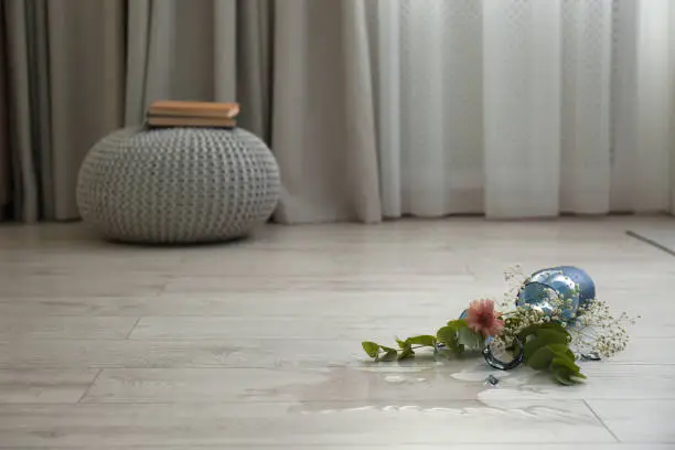 Photo of Broken blue glass vase and bouquet on floor in room. Space for text