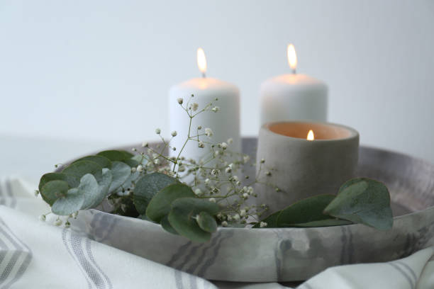 istock Beautiful eucalyptus branches, flowers and burning candles on fabric, closeup. Interior element 1388140682