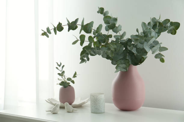 istock Beautiful eucalyptus branches, candle and bird figures on white table indoors. Interior element 1388140763