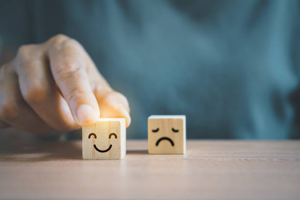 istock Close up senior customer hand choose smiling face and blurred sad face icon on wood cube block for Service rating, satisfaction survey, customer requirement concept 1388142459