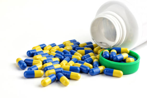White medicine jar and heap of blue-yellow capsule are scattered isolated on a white background, Antibiotic capsule.