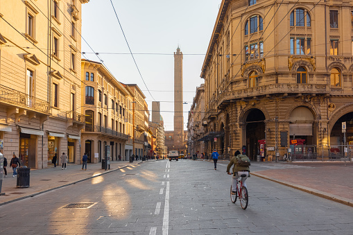 Street view with famous Asinelli towers on background in Bologna city, Italy