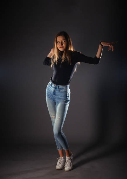 istock Attractive female model in denim jeans posing isolated on grey background. 1388149009