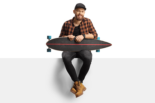 Guy posing with a longboard on a white panel isolated on white background