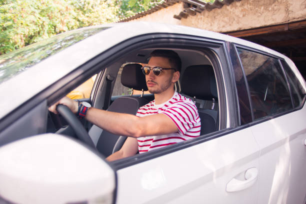 jovem bonito estacionando o carro - car driving men reversing - fotografias e filmes do acervo