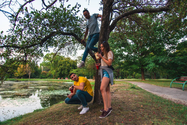 istock Young people watching their friend climbing a tree 1388150123