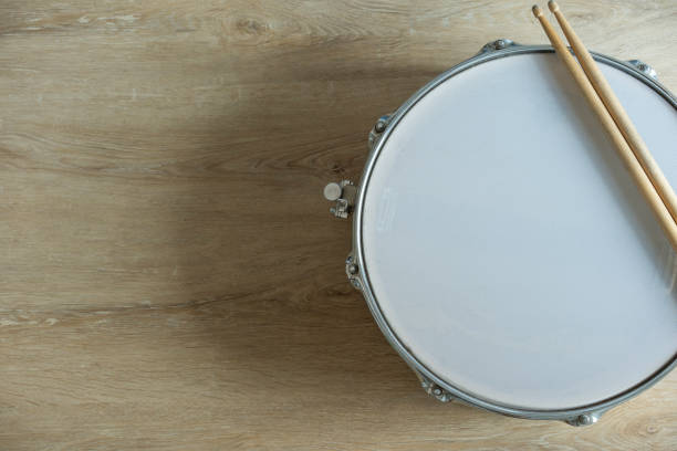 istock Drum stick and drum on wooden table background, top view, music concept 1388151177