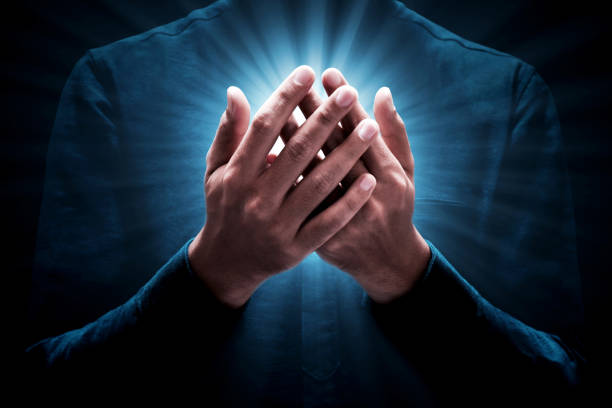Male hands emerging from darkness, cupped, with rainbow colored bright white star burst of light between
