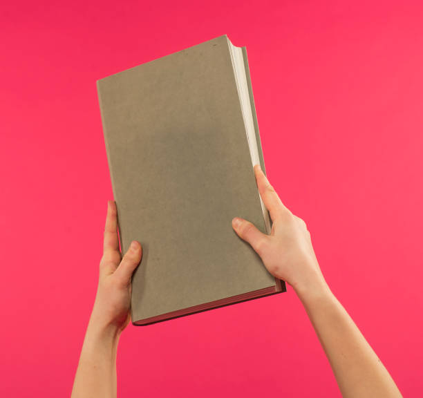 istock female hands hold a light gray book on a pink background with free space for text 1388151882
