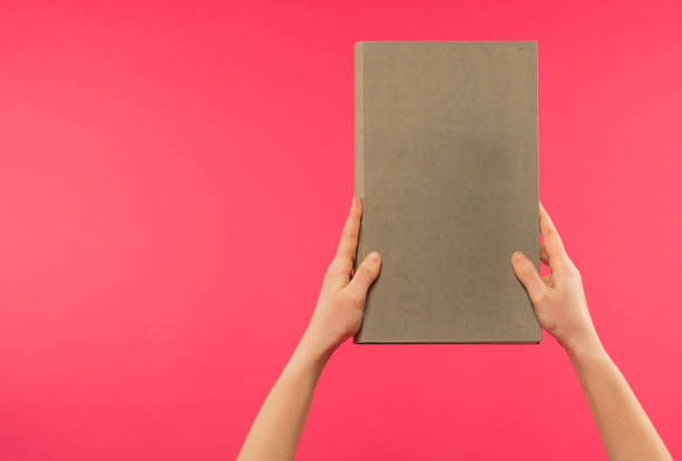 istock female hands hold a light gray book on a pink background with free space for text 1388151897