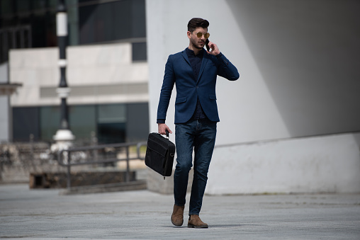 Attractive businessman is having a business talk on the phone with his partners