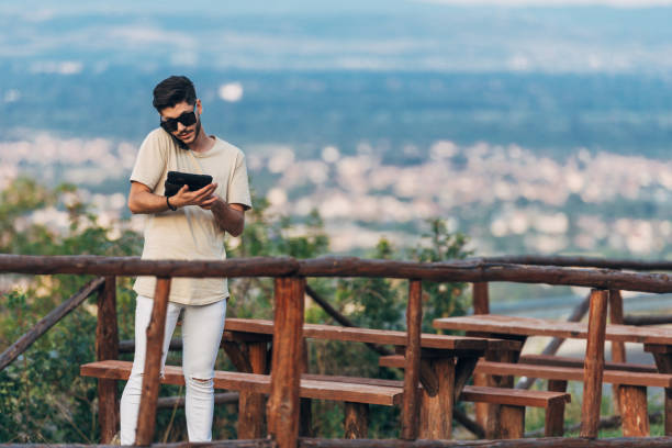 istock Freelancer man working on tablet while standing near wooden table in nature 1388152438