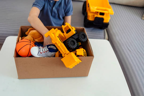 boy fait don de ses jouets emballés dans une boîte en carton. - charity and relief work donation box volunteer child photos et images de collection