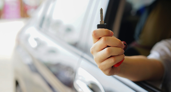 close up man hand outstretch from window's ar and hold key for rental business concept