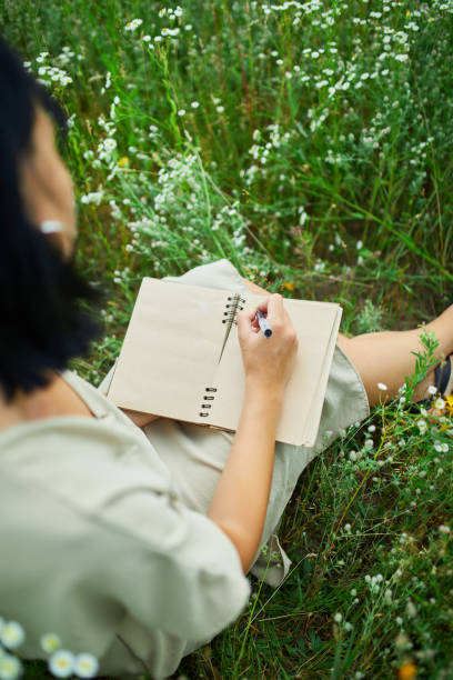 женщина с пером, пишущая или рисующая, почерк на тетради на цветущем лугу - writing diary nature ideas стоковые фото и изображения