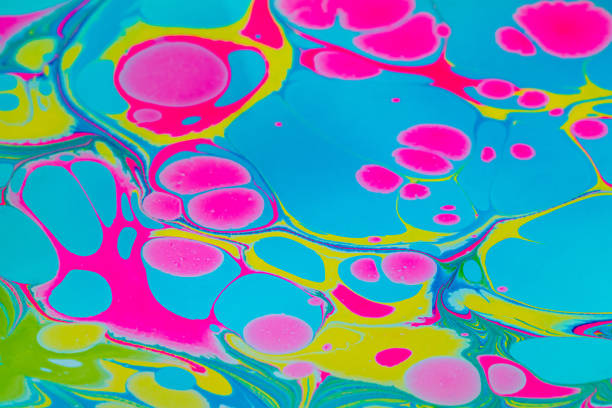 Colorful background with pink, blue and yellow marble spots in Turkish ebru technique. Unique artistic marble texture background, drawing pictures with acrylic paints on the surface of the water. Close up.