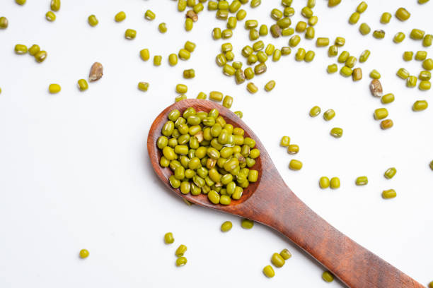 Green gram or mung bean in wooden spoon over white background.