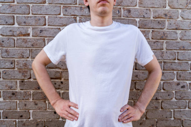 istock Man wearing mockup white t-shirt on brick wall background. Template copy space 1388161697