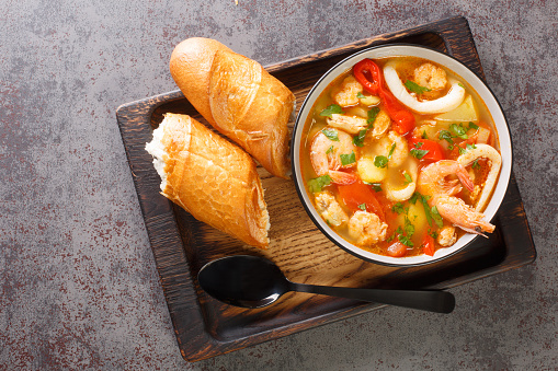 Mediterranean seafood stew with potatoes, peppers, tomatoes and onions close-up in a bowl on the table. horizontal top view from above