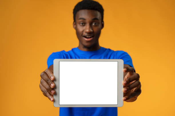istock African american man showing blank digital tablet screen with copy space in yellow studio. 1388165649
