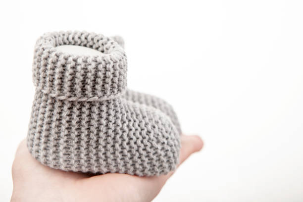 Homemade knitted baby pink booties isolated on white background