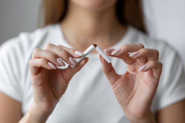 Woman quitting smoking breaks last cigarette stock photo
