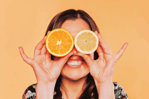 istock Close up woman holding fruit covering her eyes at studio 1388166403