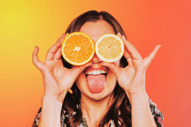 istock Close up young female holding fruit covering her eyes at studio 1388166410