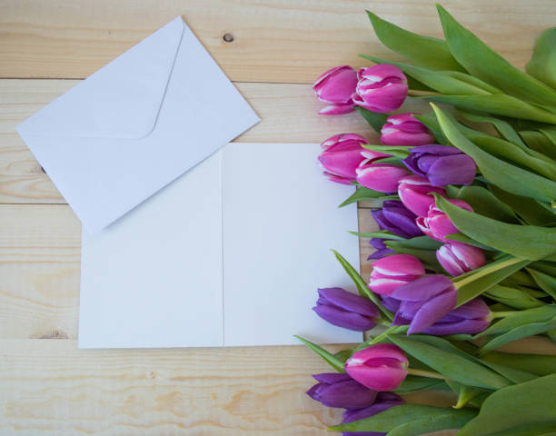 istock white card and envelope on wooden ground with tulips with space for text 1388167036