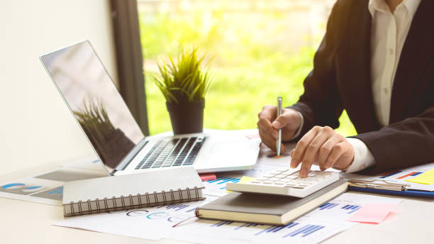 istock Hand pressing a calculator, analyzing financial documents while holding a pen in your finger. Young Asian businessman charging taxes, bills, credit card for payment, financial concept. 1388167142