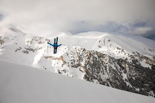 Back country skier making a back flip in high mountain terrain
