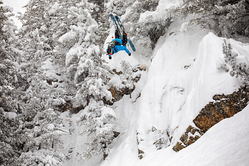 Free-skier back flipping in a back country mountain terrain