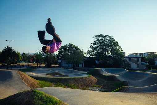 Athletic person during a side flip move in the air at the city skate playground