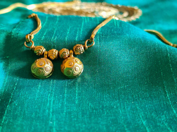 Stock photo of beautiful fancy golden Mangalsutra with golden chain on sea green nursery color on background, captured captured at Bangalore, Karnataka, India. focus on object. stock photo