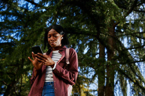 istock Woman walking and typing on the phone in park 1388170621
