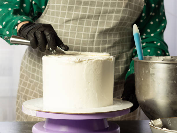 istock the pastry chef makes a white cream cake using a spatula.align the edges of the cake 1388171740