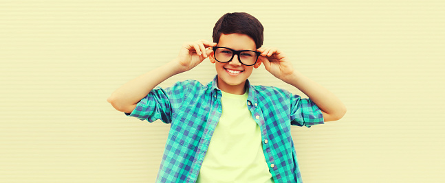 Portrait of happy smiling teenager boy in eyeglasses on background